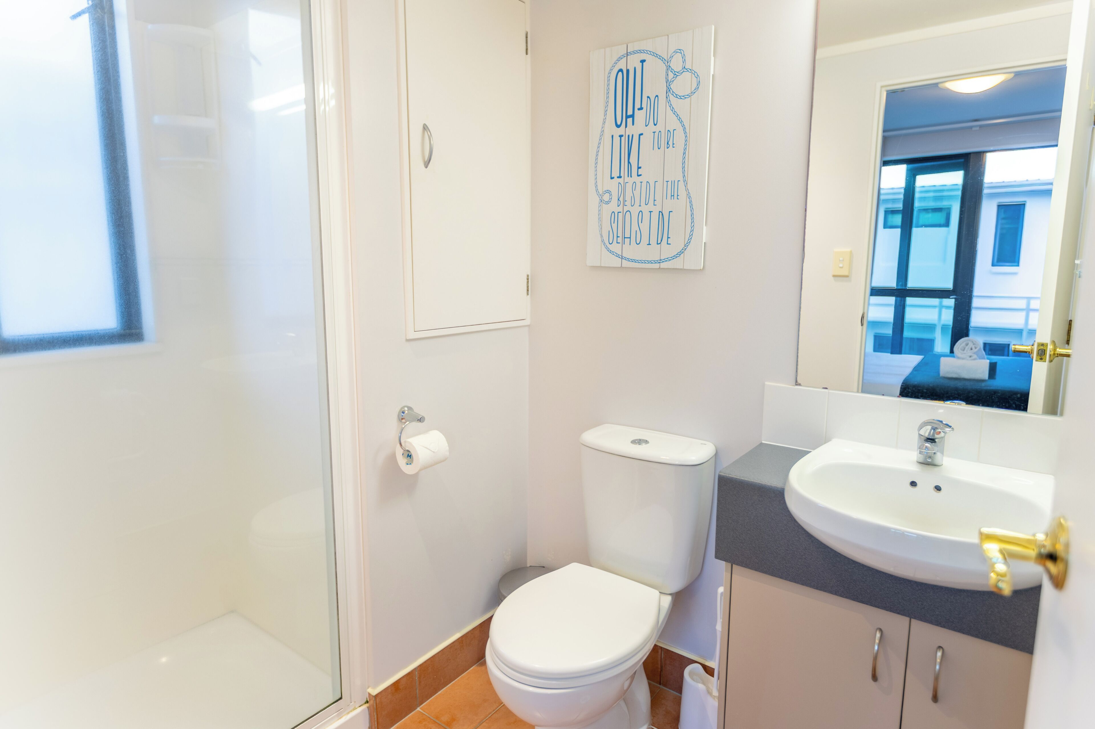 A bathroom with a toilet, sink, and a mirror.