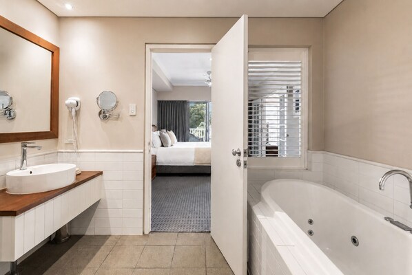 Un baño moderno con bañera, lavabo y espejo.