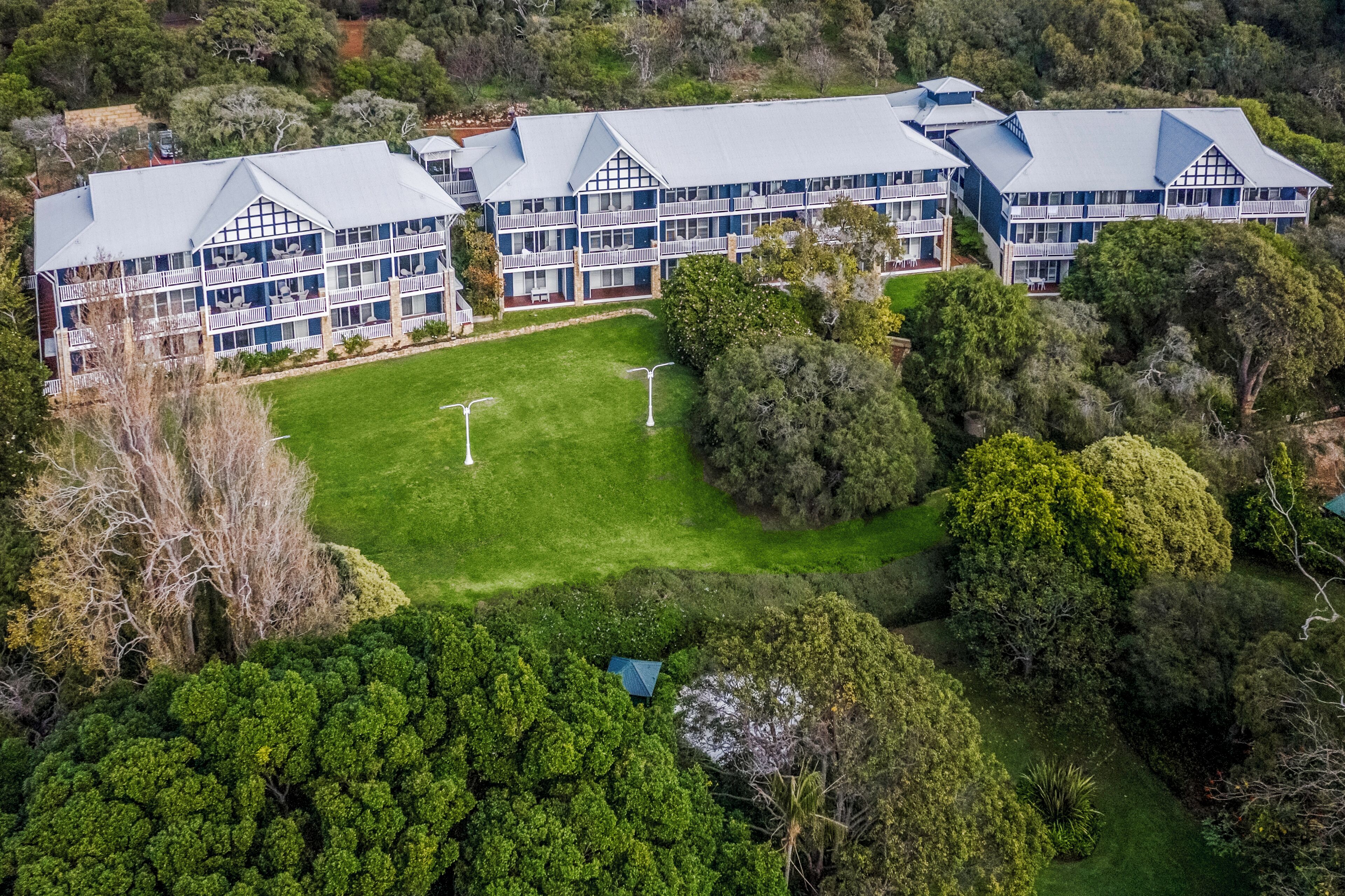 A large hotel with multiple buildings, a central courtyard, and surrounding greenery.