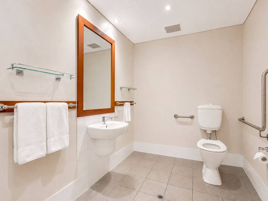 Une salle de bain moderne équipée d’un lavabo, d’un miroir, de toilettes et de barres d’appui.