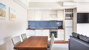 Una cucina moderna con mobili bianchi, una parete di fondo blu e un forno a microonde integrato.
