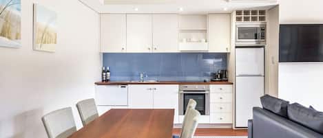 Una cocina moderna con armarios blancos, un salpicadero azul y un microondas empotrado.
