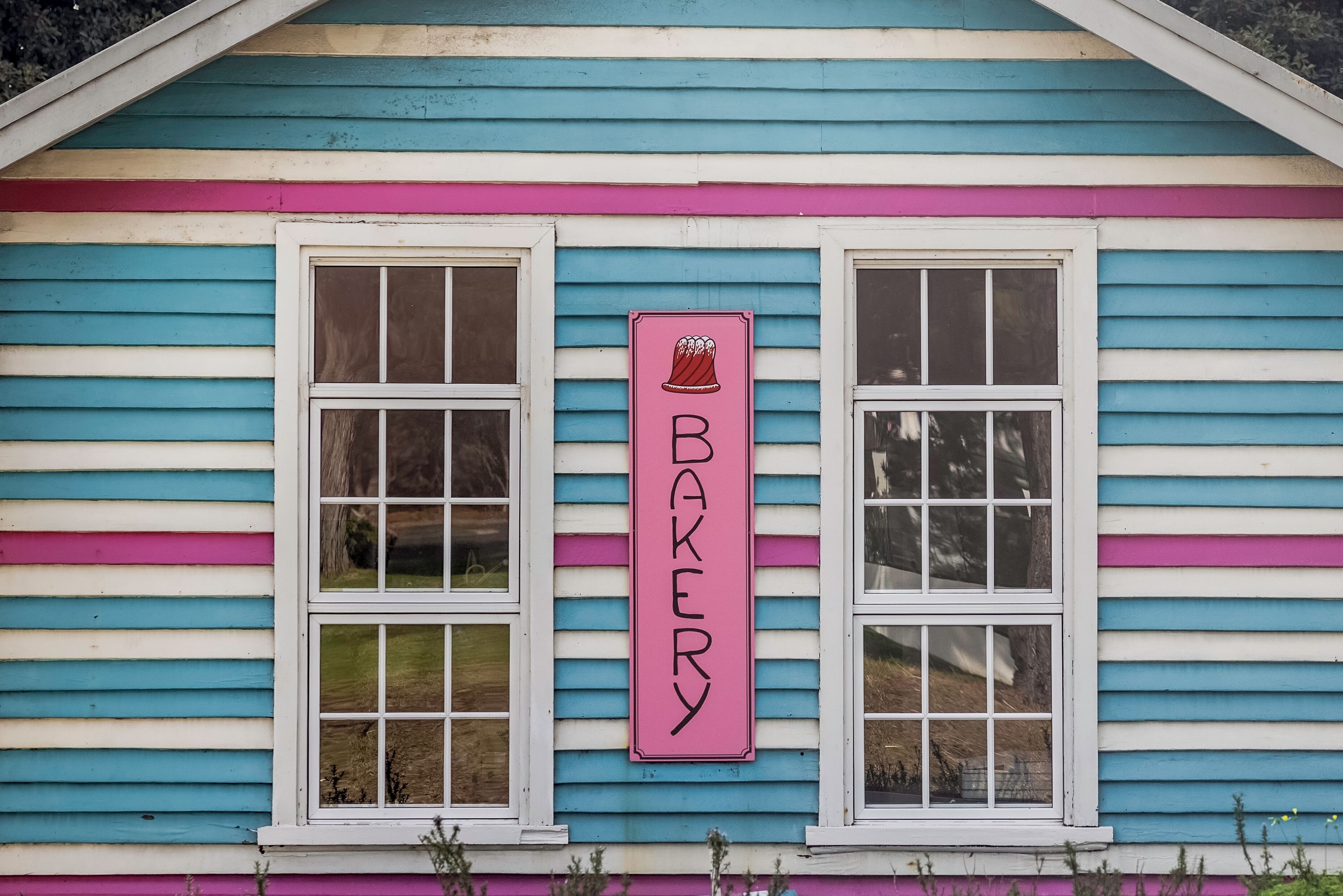 A colorful building with a sign that reads 'BAKER' and two windows.