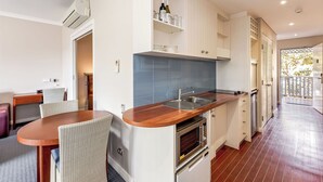 Una cucina compatta con forno a incasso, lavello e zona pranzo con tavolo e sedie.