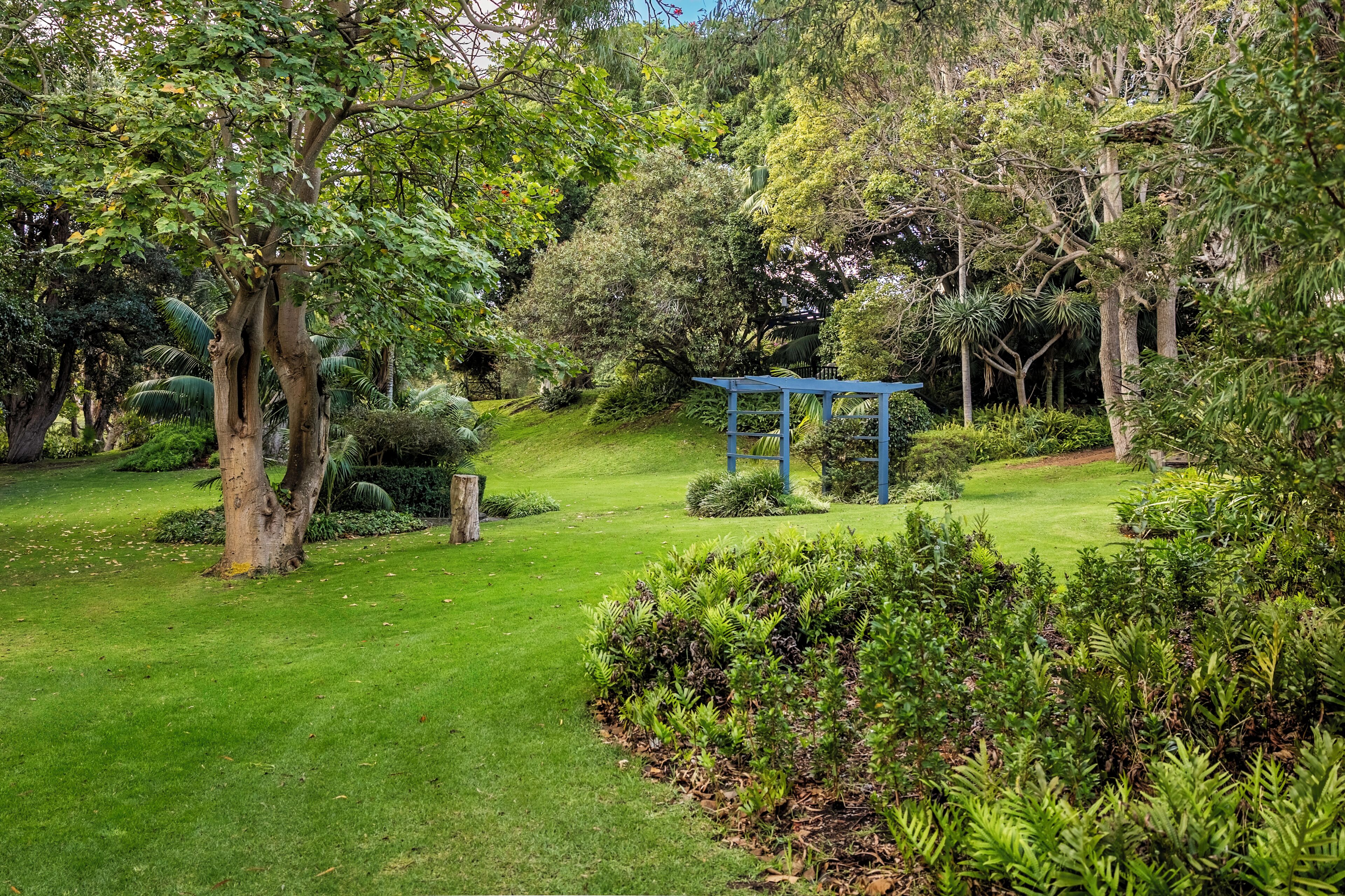 A well-maintained garden with a gazebo, various trees, and a grassy lawn.