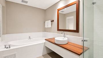 A modern bathroom with a bathtub, a sink, and a large mirror.
