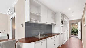 Una cucina moderna con mobili bianchi, un piano di lavoro in legno e uno schienale piastrellato.