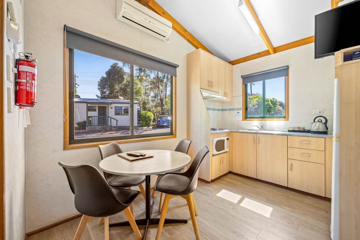 A modern kitchen with wooden cabinets, a microwave, and a window overlooking a residential area.