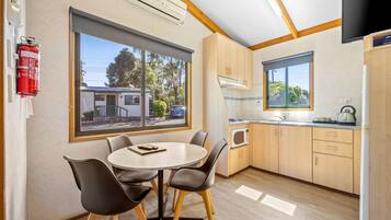 A modern kitchen with wooden cabinets, a microwave, and a window overlooking a residential area.