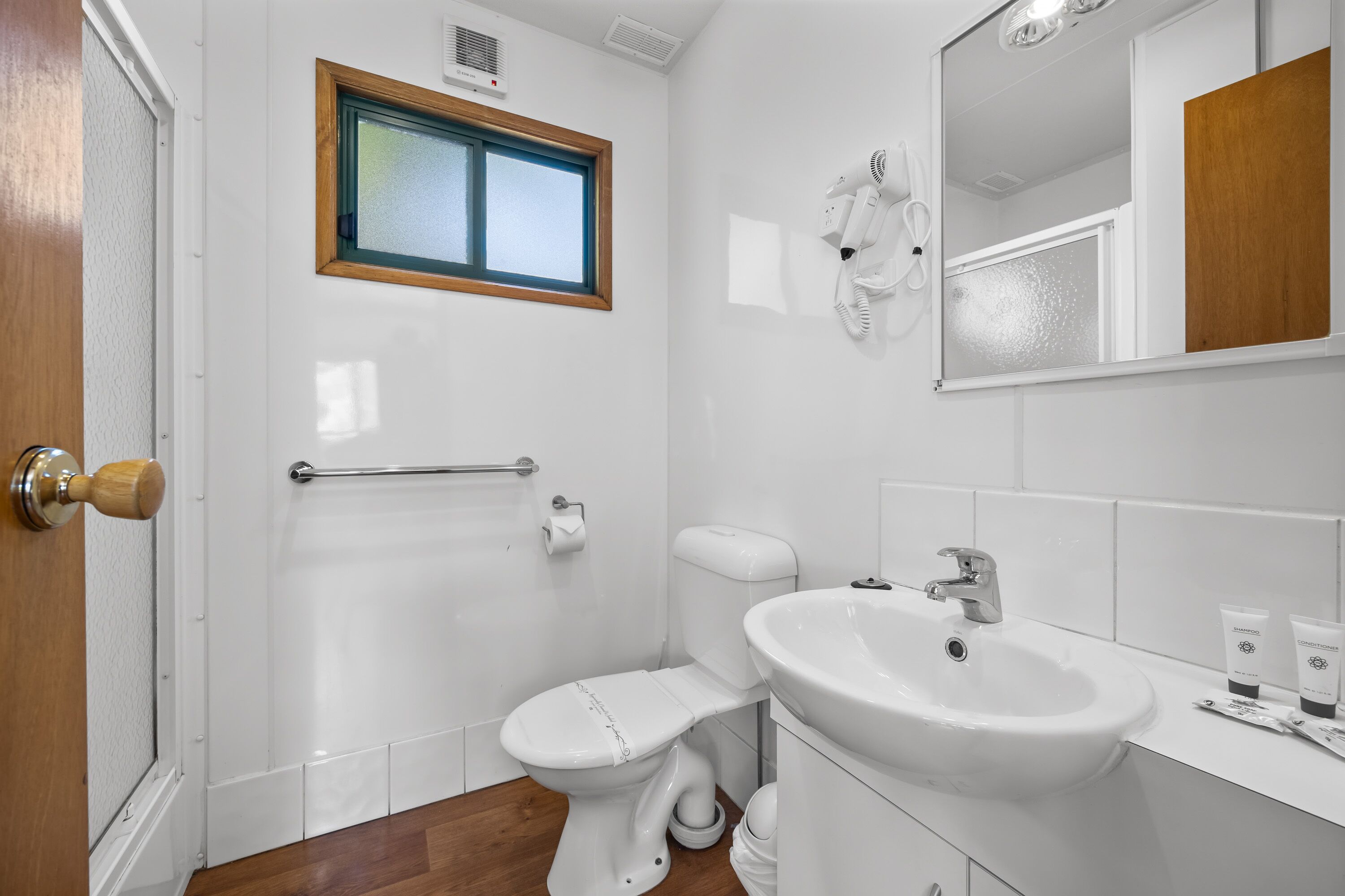 A modern bathroom with a toilet, sink, and hand dryer.