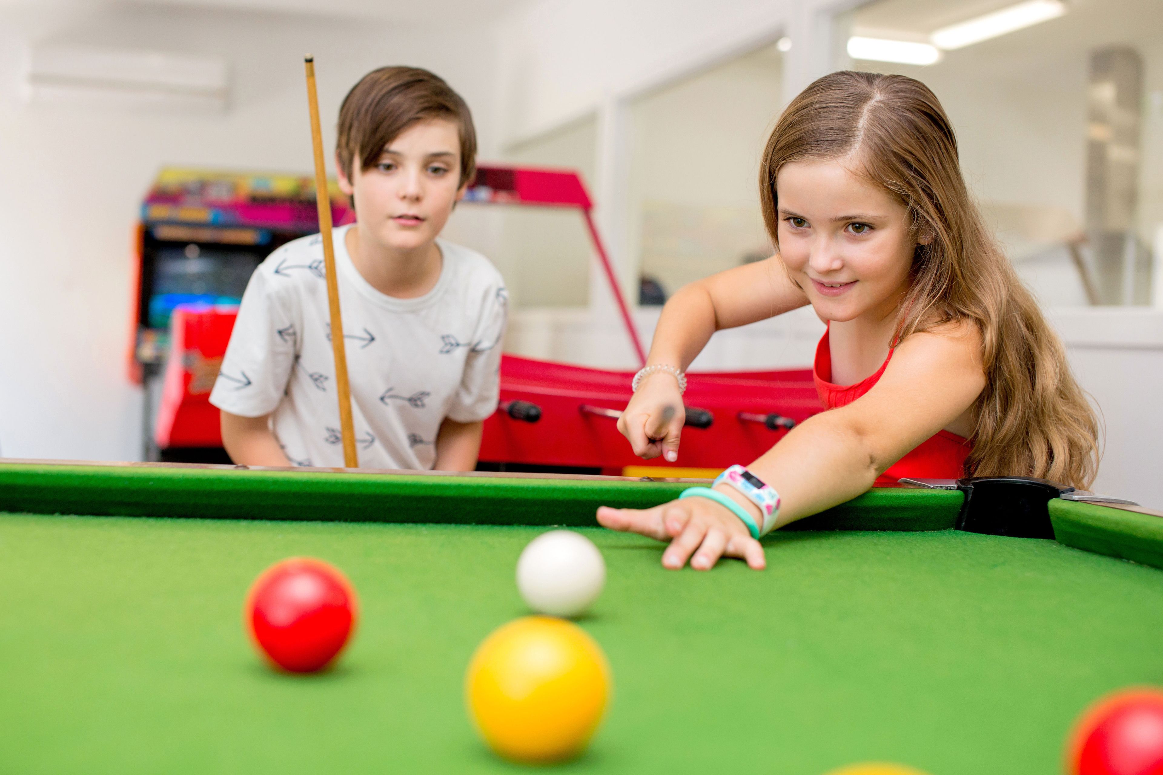 A pool table with balls and a red tablecloth.