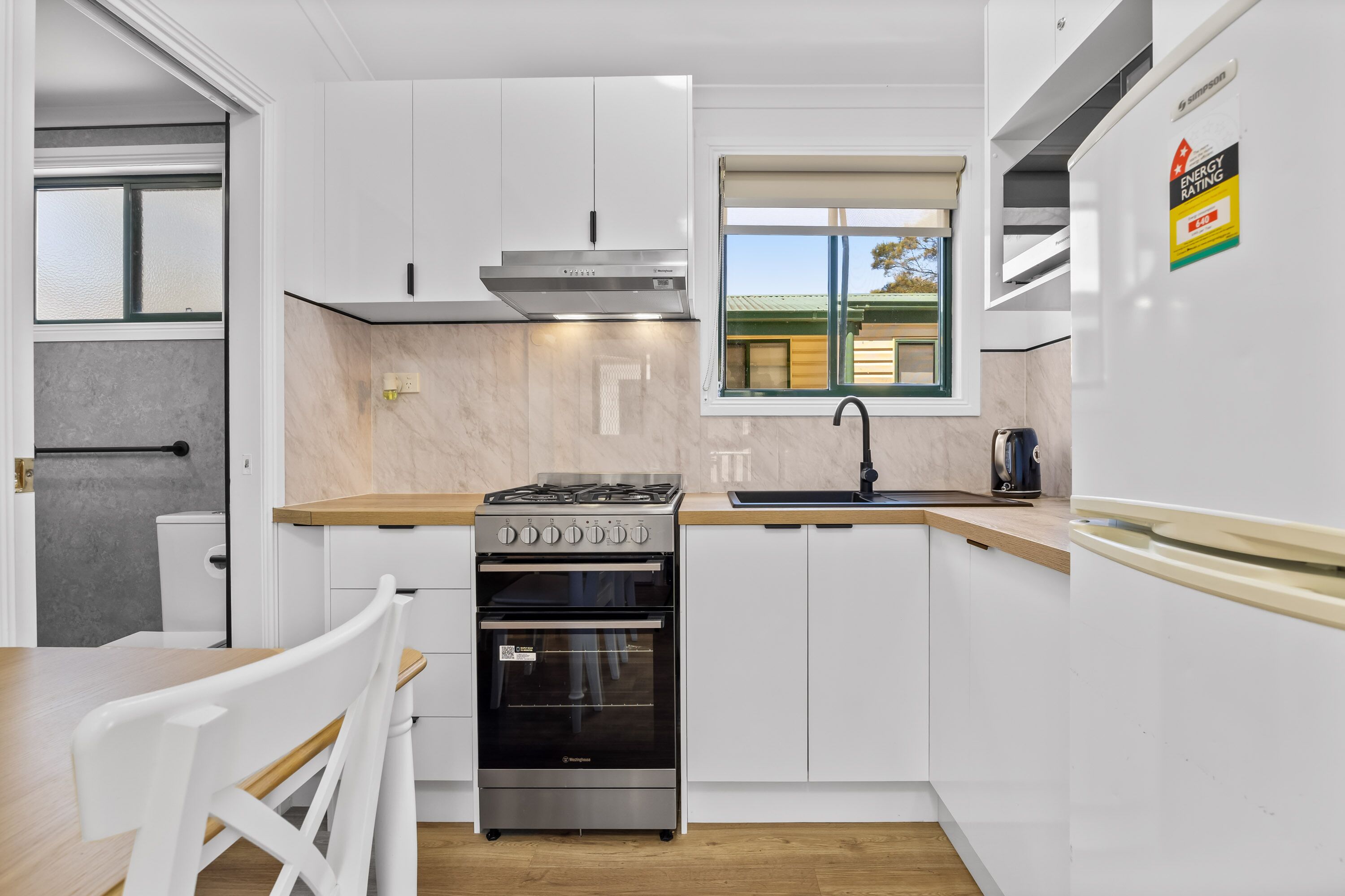 A modern kitchen with white cabinets, a stainless steel stove, and a built-in oven.