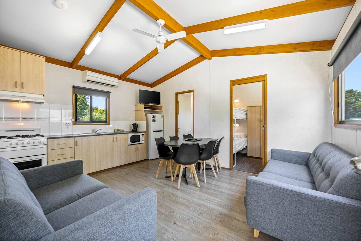 A compact kitchen with modern appliances, a dining area with a round table and chairs, and a cozy seating area with sofas.