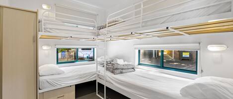 A compact, well-lit room with bunk beds, a window with a view of the outside, and a small storage cabinet.