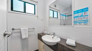A modern bathroom with a white sink, a towel rack, a mirror, and a window.