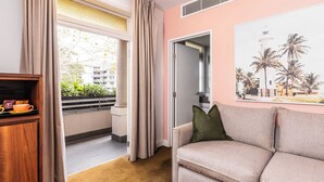 A living room with a beige sofa, a wooden cabinet, and a window with curtains. - The Lucky Hotel (Newcastle)