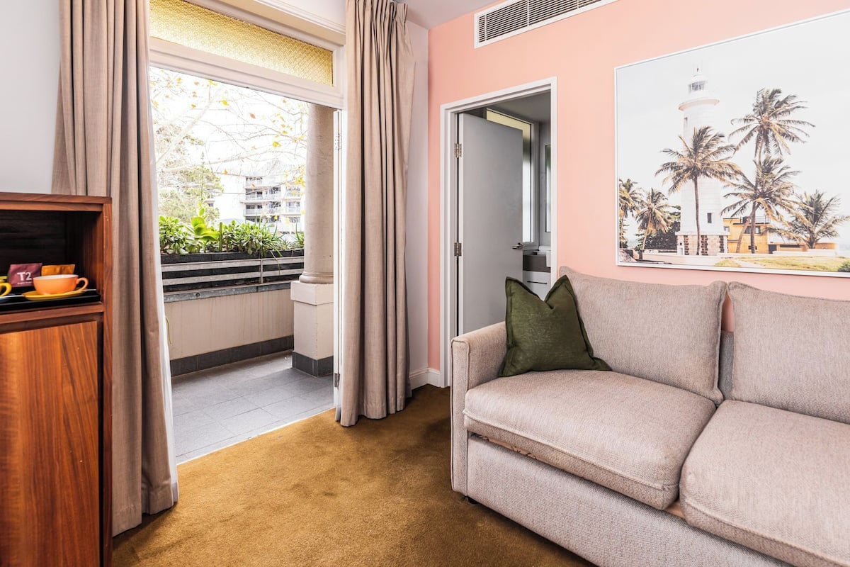 A living room with a beige sofa, a wooden cabinet, and a window with curtains.