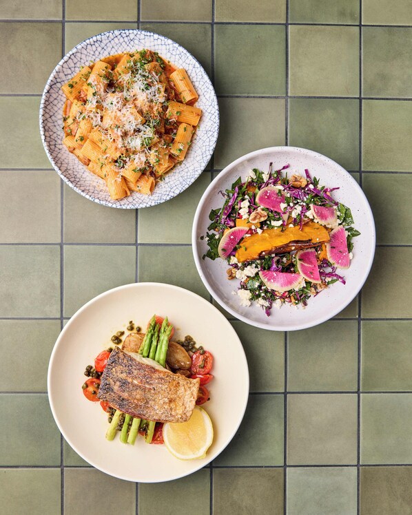 Three plates of food on a tiled surface.