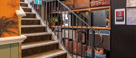 Un escalier orné de vieilles valises disposées sur des étagères au-dessus.