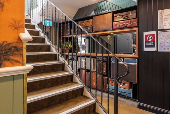A staircase with vintage suitcases arranged on shelves above.