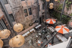 An outdoor dining area with wicker pendant lights, tables, and orange and white striped umbrellas. - The Lucky Hotel (Newcastle)