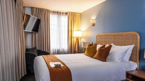 A hotel room with a large bed, a flat-screen TV mounted on the wall, a bedside lamp, and a chair. - The Lucky Hotel (Newcastle)