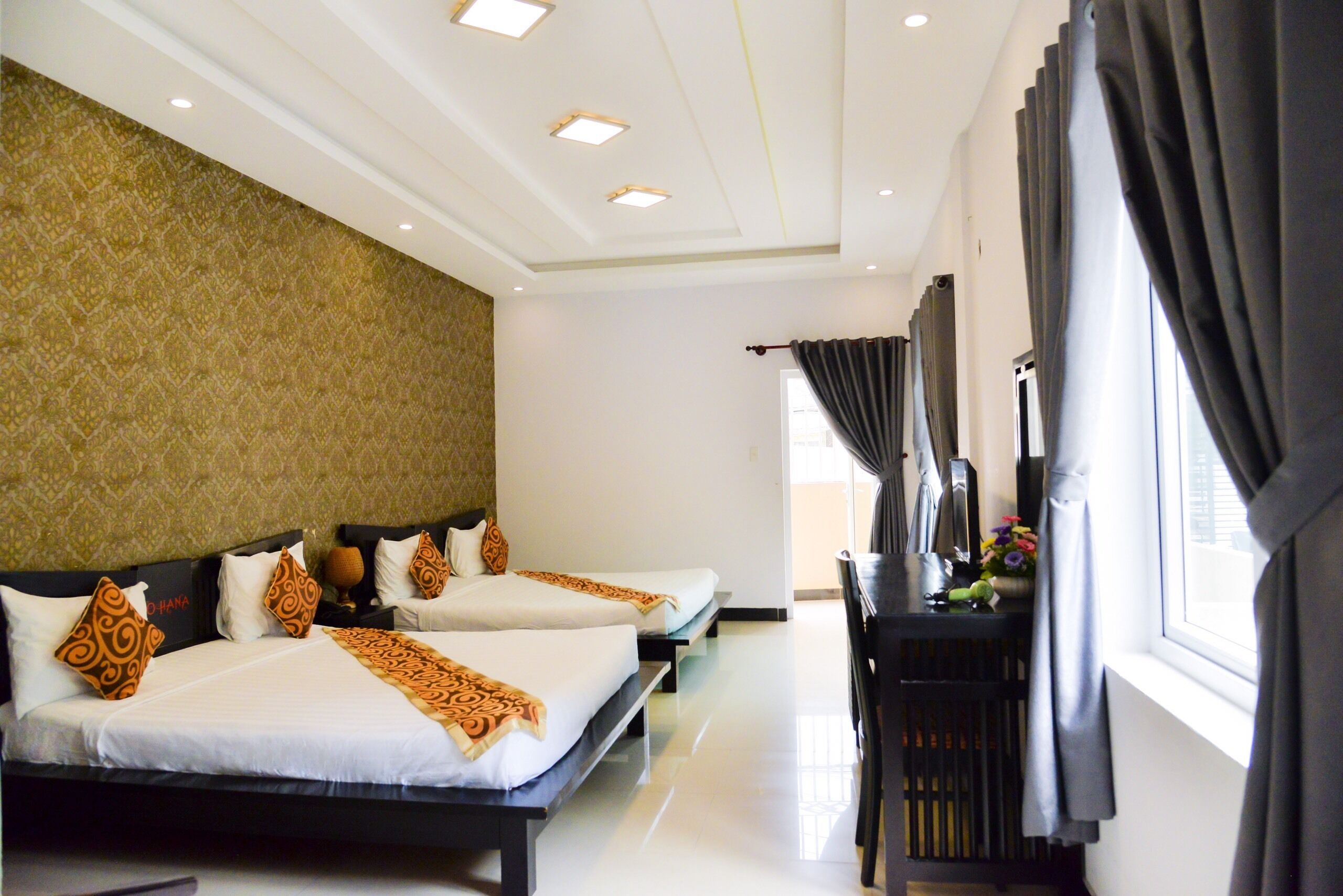 A hotel room with two beds, a desk, and a window with curtains.