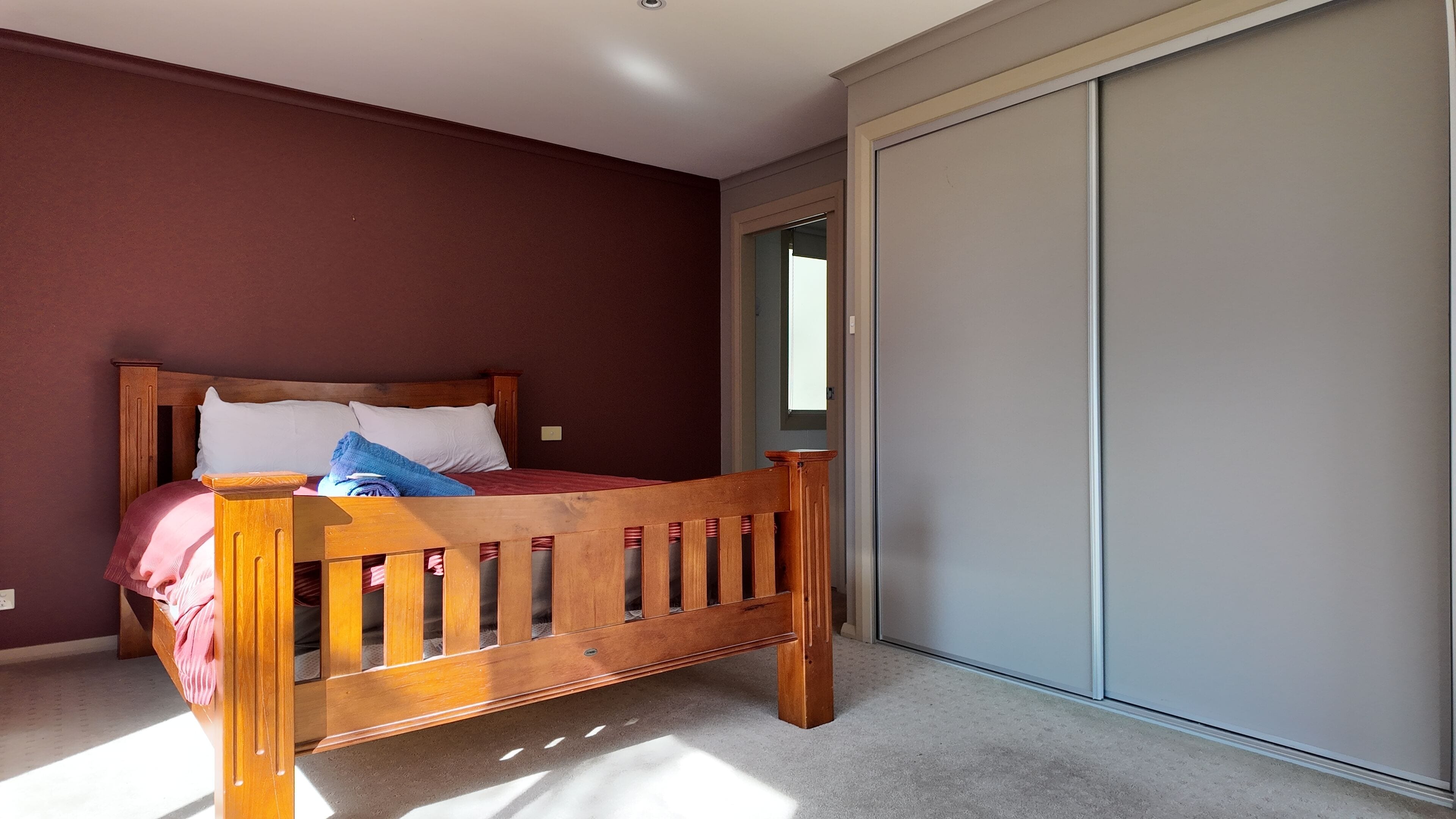 Un dormitorio con cama de madera, un armario y suelo cubierto de alfombra.