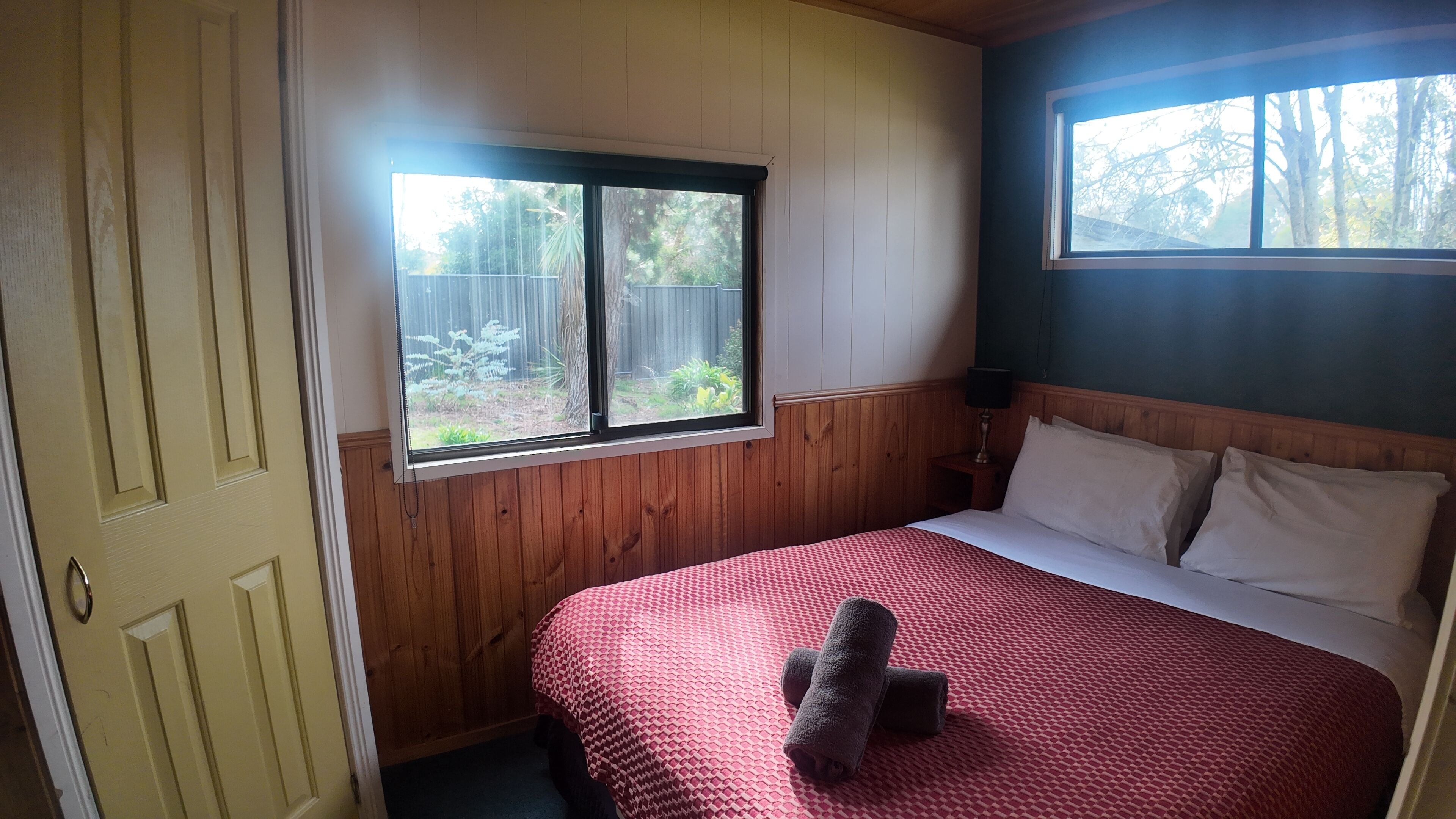 A bedroom with a bed, a window, and a door.