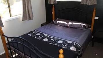 A bedroom with a bed, a window with curtains, and a dark wall.