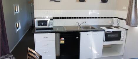 A compact kitchen with a microwave, sink, stove, and dishwasher.