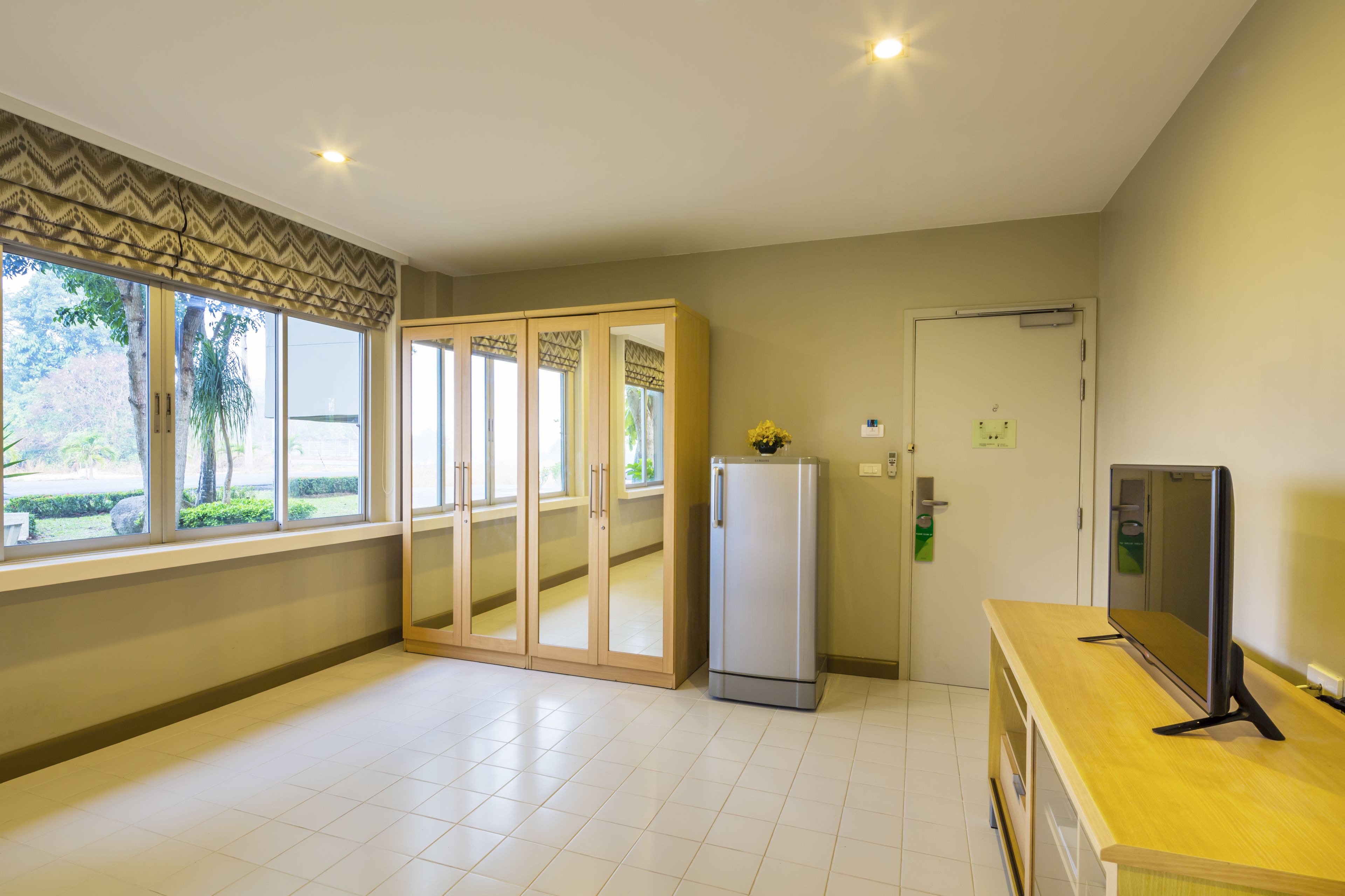 Een ruime kamer met grote ramen, een koelkast, een televisie en een houten aanrecht.