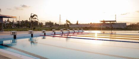 A swimming pool with lane dividers and a sunset in the background.