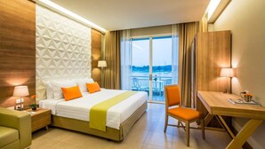 A hotel room with a bed, a desk, a chair, and a view of the outside. - Pattana Sports Resort (Si Racha)