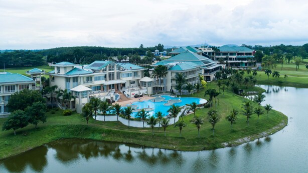 A resort with multiple buildings, a large swimming pool, and a lake. - Pattana Sports Resort (Si Racha)