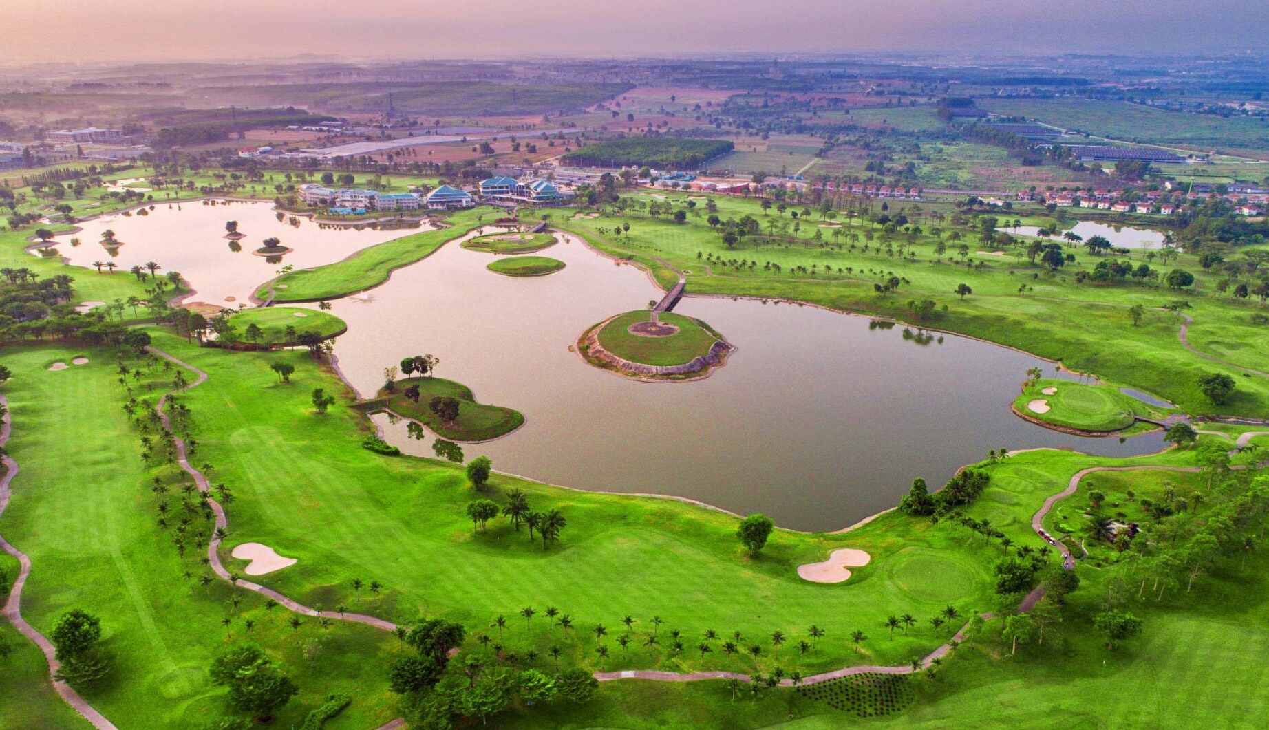 An aerial view of a golf course with multiple ponds, green fairways, and sand bunkers.