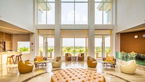 A spacious lobby with high ceilings, large windows, and a central seating area with multiple chairs and a large ottoman. - Pattana Sports Resort (Si Racha)