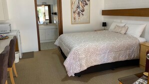 A bedroom with a bed, a nightstand, a dresser, a mirror, and a painting on the wall. - Orana Motor Inn (Irymple)