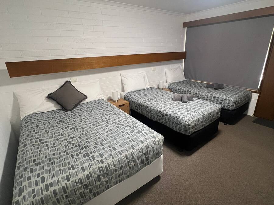 Ein Hotelzimmer mit zwei Betten, einem Holzkopfende, einer weißen Ziegelwand und einer Deckenleuchte.
