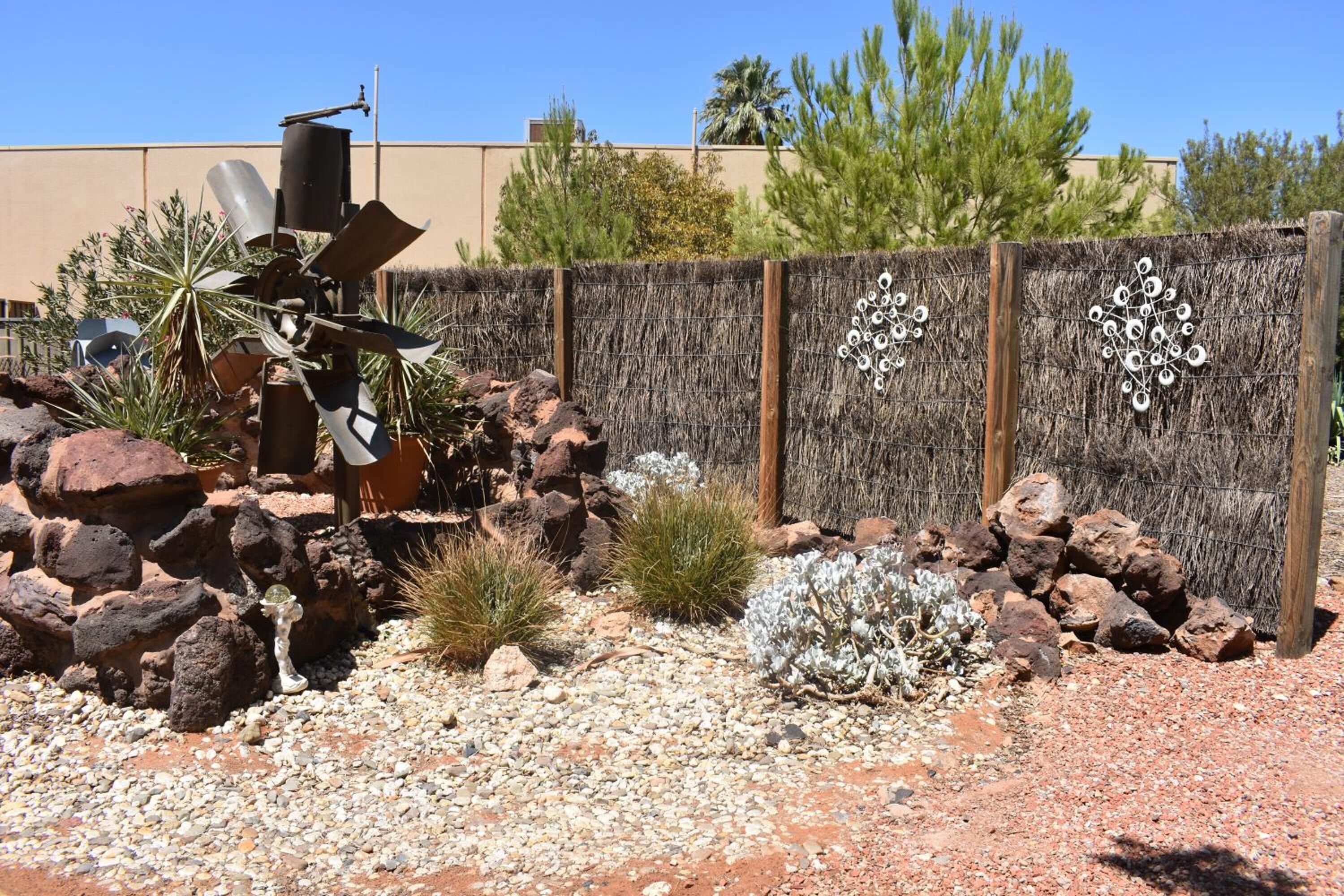 A garden with rocks, cacti, and a decorative fence.