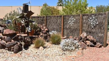 A garden with rocks, cacti, and a decorative fence.