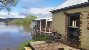 A riverside cabin with a deck, a covered porch, and a large window. - Ratho Farm (Bothwell)