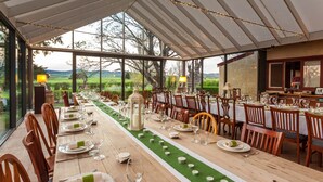 A long dining table set for a meal with chairs, candles, and a view of the countryside. - Ratho Farm (Bothwell)