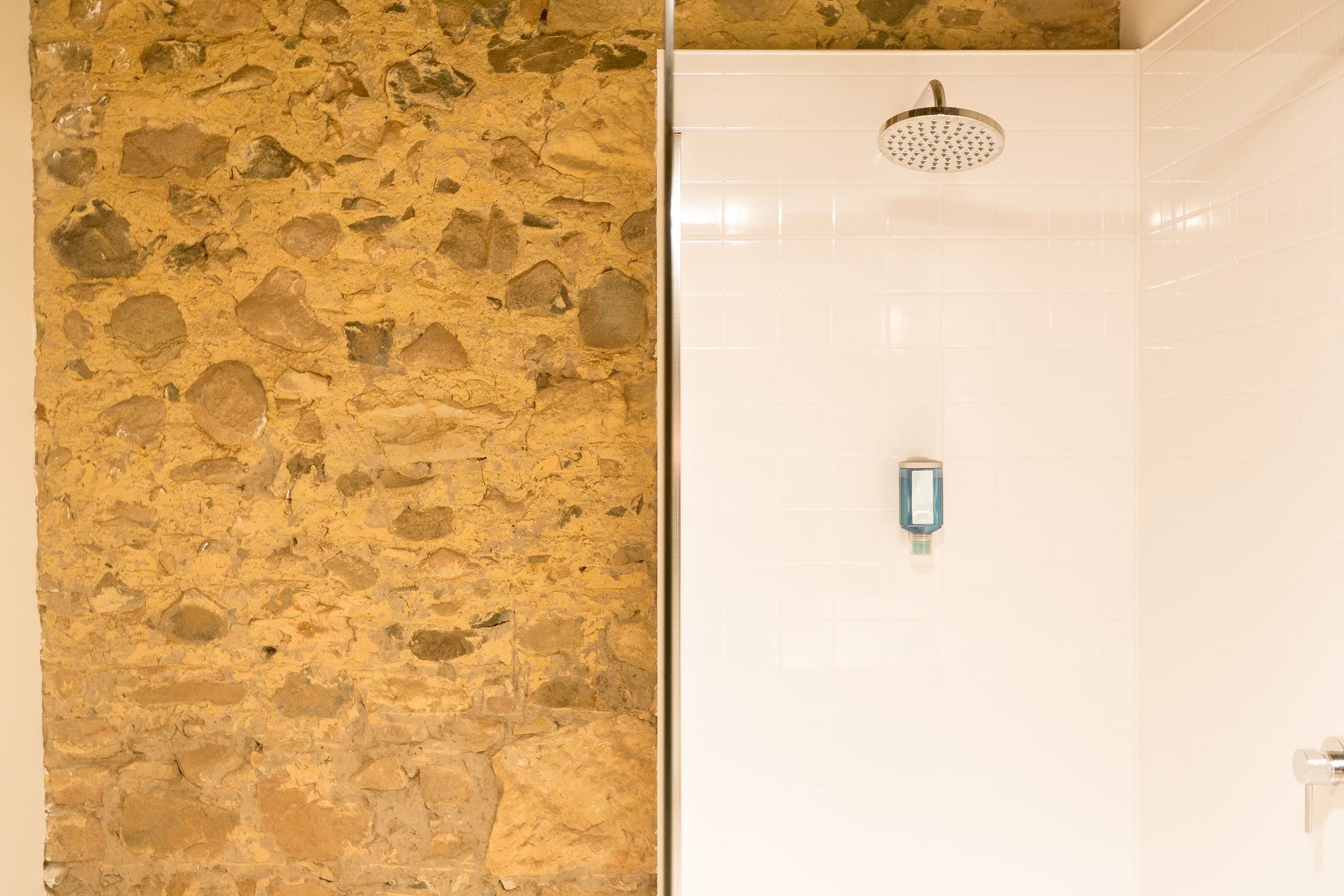 A bathroom with a stone wall and a shower area.