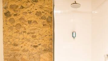A bathroom with a stone wall and a shower area.