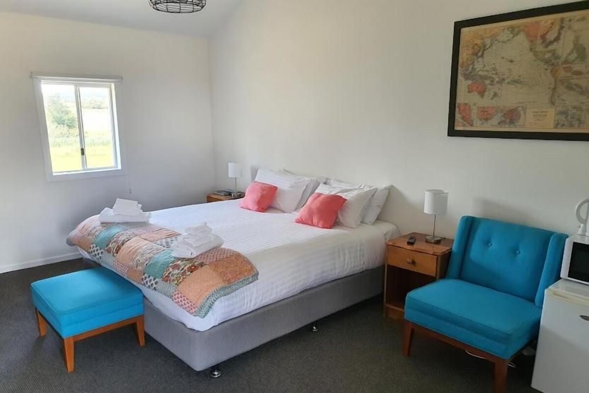 A bedroom with a bed, bedside tables, a chair, a desk, and a window.