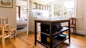 A room with a wooden table, chairs, a bed, a window, and a radiator. - Ratho Farm (Bothwell)