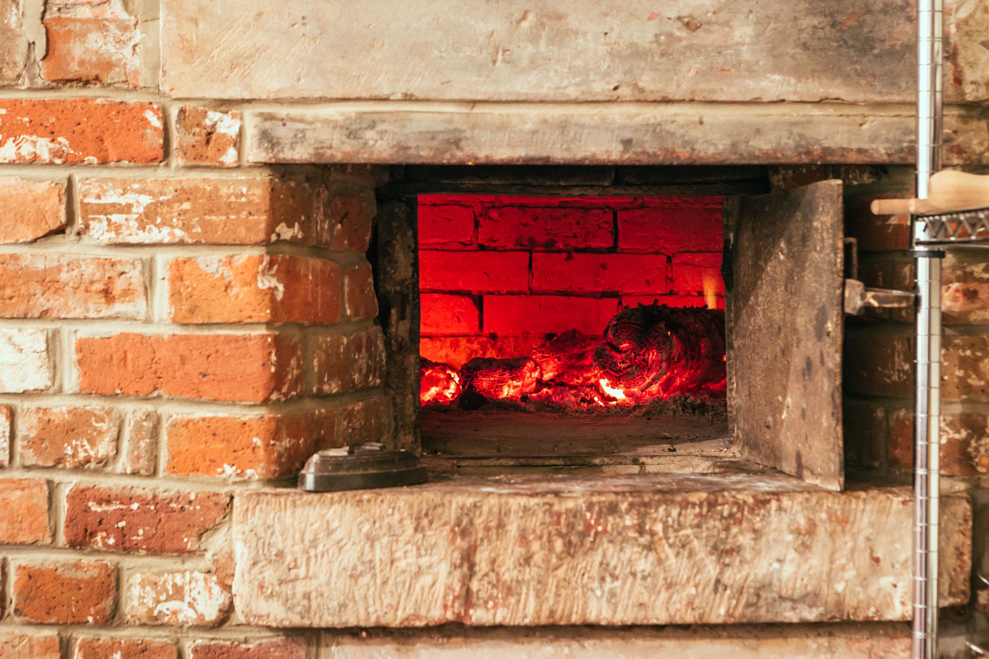 A brick oven with visible fire inside, indicating a cooking or baking function.