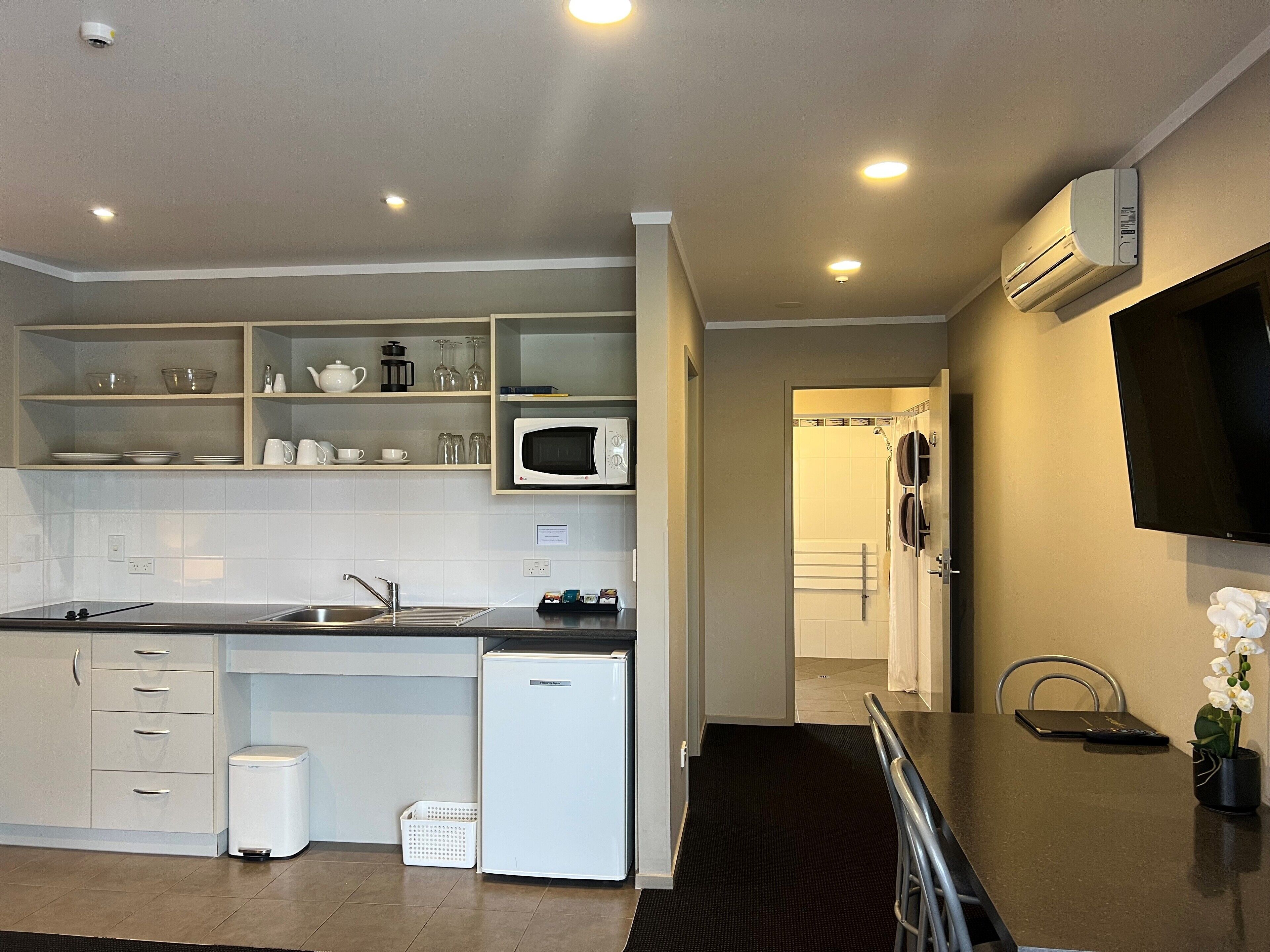 A modern kitchen with white cabinetry, a microwave, and a small refrigerator.