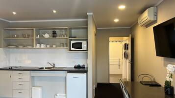 A modern kitchen with white cabinetry, a microwave, and a small refrigerator.